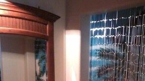 A room with a wooden-framed window, a view of a pool, and a wall-mounted picture.
