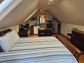 Ein Schlafzimmer mit Bett, einer Küchenzeile und einer Essecke in einer Loft-Wohnung.