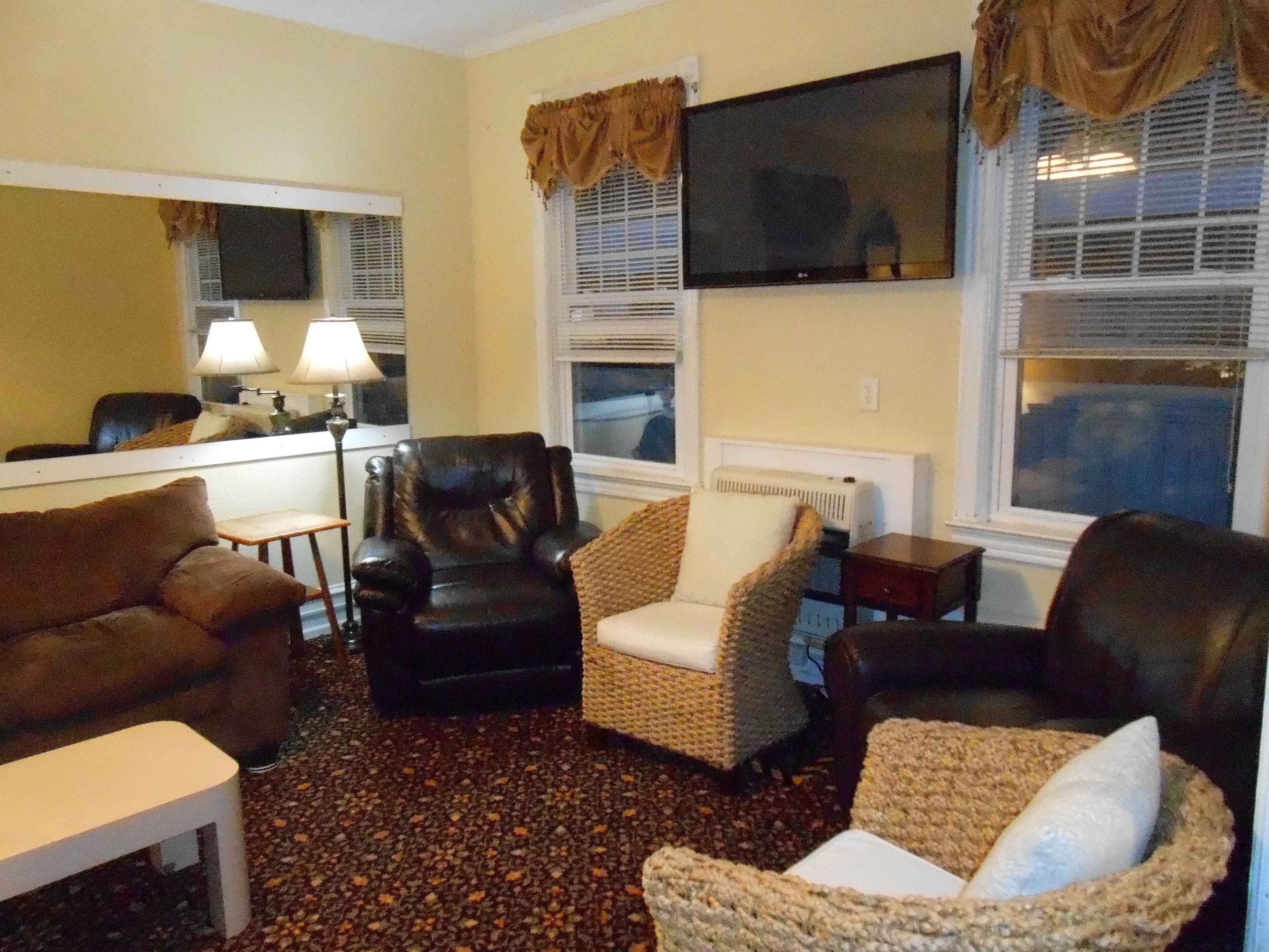 A living room with a sofa, armchair, and a TV mounted on the wall.