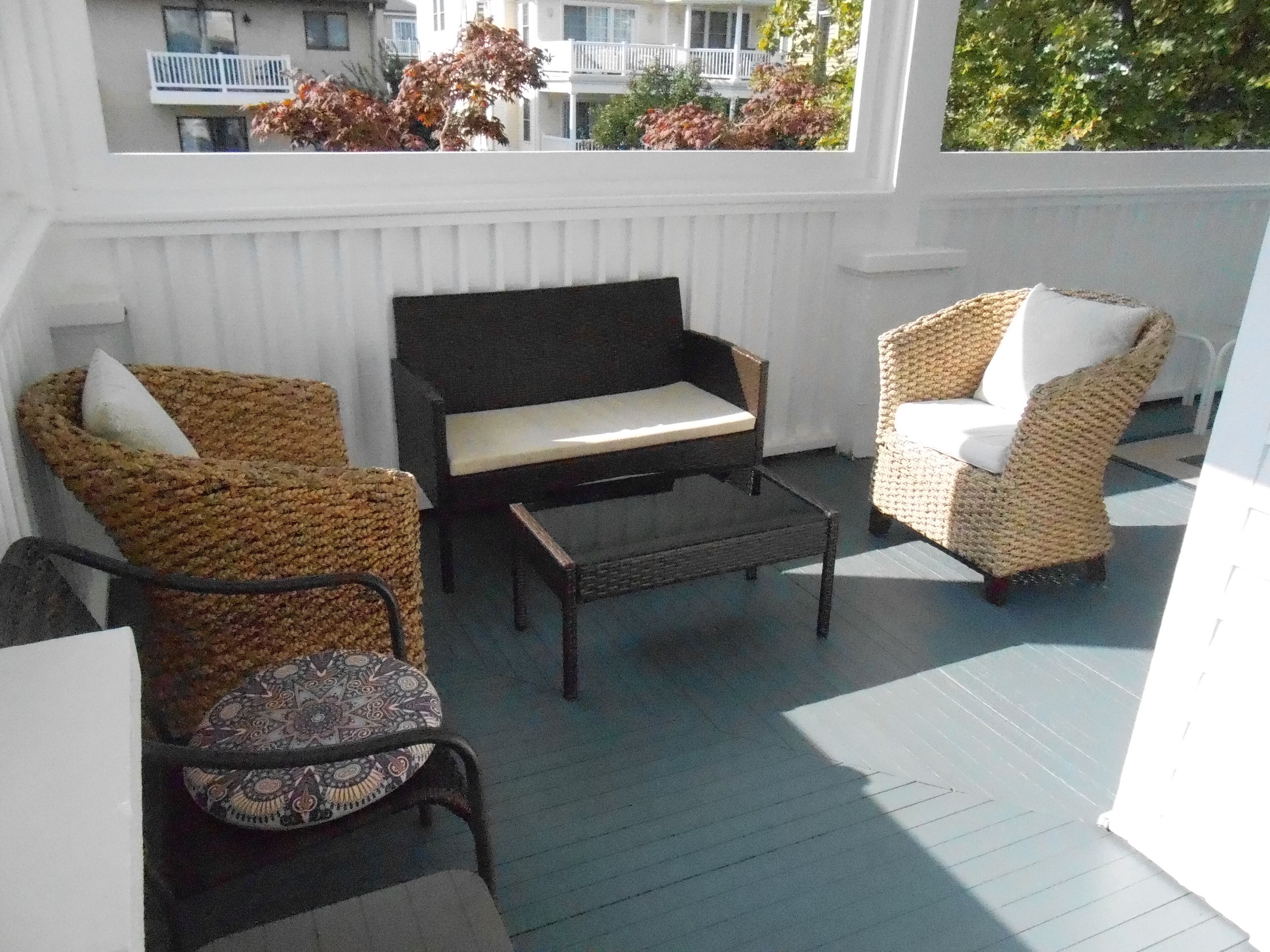 Een overdekt terras met rieten meubilair, een bank en een tafel.