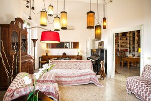 A cozy living room with a piano, a large red lamp, and a bookshelf.