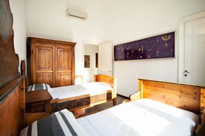 A room with two wooden beds, a large wardrobe, and a wall-mounted artwork.