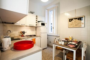 A modern kitchen with white cabinets, a red baking dish, a gas stove, and a microwave.
