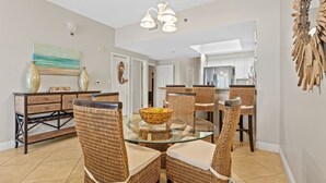 Un coin repas avec des chaises en osier, une table en verre et un saladier rempli de fruits.
