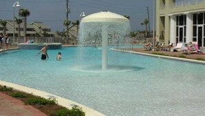 Une piscine agrémentée d’une fontaine, entourée d’une clôture et de palmiers.