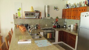 Una cucina con piani in granito, un fornello, un lavello, mobili in legno e un frigorifero.