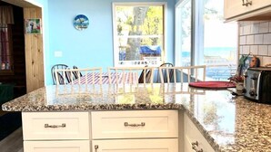 A kitchen with white cabinets, granite countertops, and a view of the outdoors.