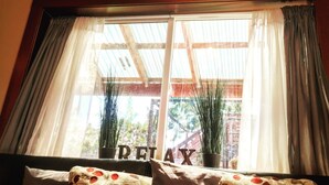 Ein Zimmer mit einem großen Fenster, einem Deckenventilator und einem Schild mit dem Aufschrift 'RELAX' am Fensterbrett.