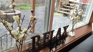 Ein Fensterbrett mit einem 'RELAX'-Schild und zwei klaren Glasvasen mit weißen Blumen.