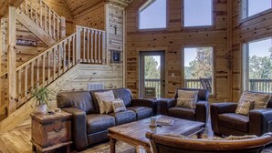 Een houten cabin met een wenteltrap, leren banken, een bijzettafeltje en grote ramen.