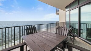 A balcony with a table and chairs overlooking a body of water. - Phoenix West 2205 by Liquid Life (Orange Beach)