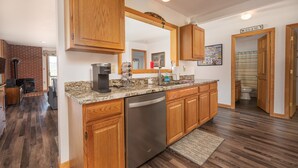 A kitchen with wooden cabinets, a dishwasher, and a granite countertop.