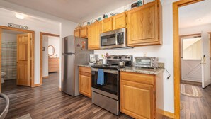 A kitchen with wooden cabinets, stainless steel appliances, and a microwave.