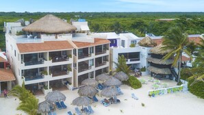 Hotel com vários andares, localização à beira-mar e área de piscina com guarda-sóis.