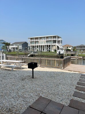 A beachfront property with a multi-level building, a wooden deck, and a gravel walkway.