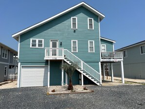 A two-story house with a white front door, a garage, and a balcony with a railing.