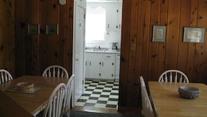 A dining room with a wooden table and chairs, a checkered floor, and a view into a kitchen with white cabinets and a window. - Only 1.5 Blocks To Ocean, 1-3 blocks of restaurants, shops, bars. Come enjoy! (Rehoboth Beach)