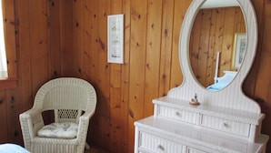 A room with wooden walls, a wicker chair, a white dresser with a mirror, and a framed picture on the wall. - Only 1.5 Blocks To Ocean, 1-3 blocks of restaurants, shops, bars. Come enjoy! (Rehoboth Beach)