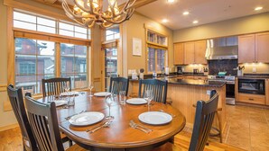 Un comedor espacioso con una gran mesa de madera dispuesta para seis personas, rodeada de sillas.