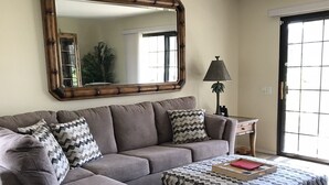 A living room with a sectional sofa, ottoman, and a large mirror on the wall. - South Palm Springs Condo - Fantastic Mountain Views! (Palm Springs)