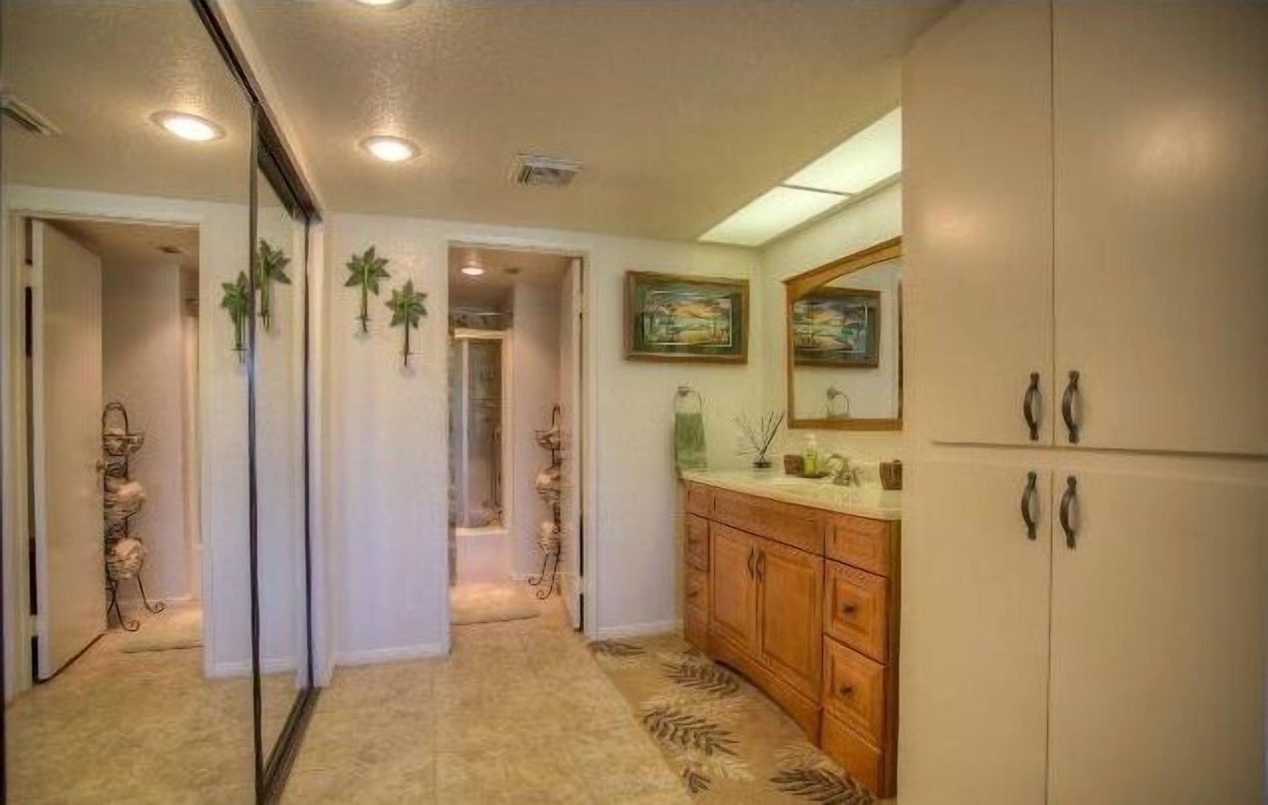 A hallway with a carpet, wooden cabinets, and a refrigerator.