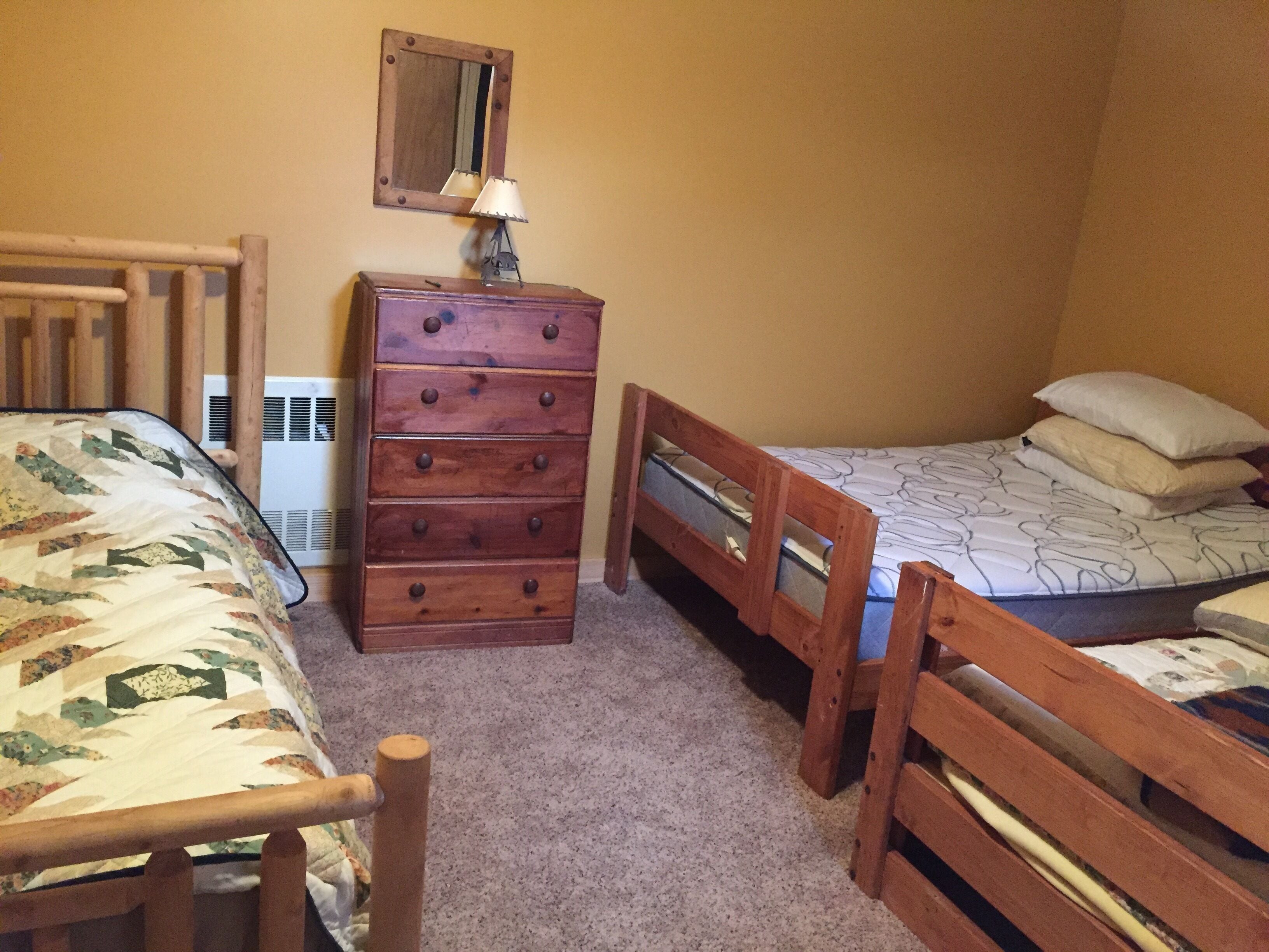 A bedroom with two wooden beds, a wooden dresser, a mirror, and a radiator.