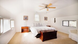 A bedroom with a bed, a nightstand, a wooden bench, a ceiling fan, a window, and a wall clock. - Charming 1870 Farmhouse in the Heart of Petaluma
 (Petaluma)