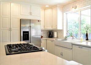 A modern kitchen with white cabinetry, a stainless steel refrigerator, a gas stove, and a window with a view of greenery. - Walking Distance To Old Town Scottsdale-Spring Training, Shopping and Galleries (Scottsdale)