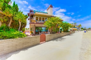 Un hôtel situé en bord de mer, avec une structure à deux étages, un balcon et une vue sur l’océan.