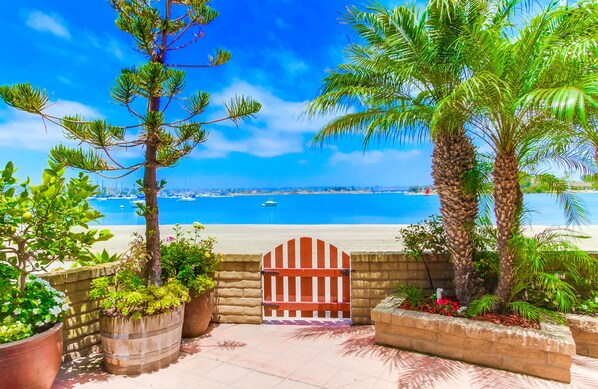 Une vue sur la côte, avec une porte en bois, des plantes en pot et un ciel bleu dégagé.