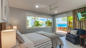 Un dormitorio con cama, televisor y vista al océano.