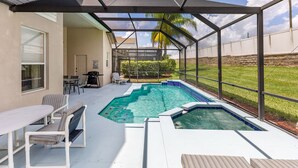 A covered outdoor swimming pool with a patio area, including seating and a table.