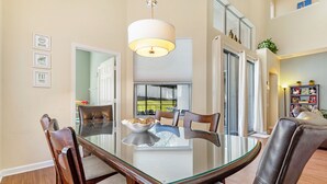A dining area with a glass table, leather chairs, and a pendant light.