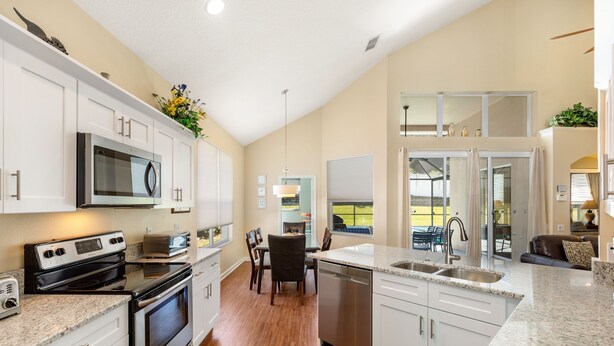 A modern kitchen with white cabinets, stainless steel appliances, and a granite countertop.
