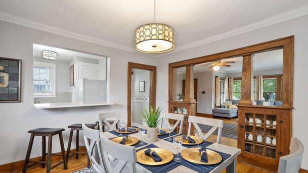 A dining area with a wooden table set for four, white chairs, and a blue patterned rug. - Walk to ND and Eddy Street, ProCleaned * Comfy * Updated (South Bend)