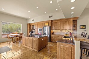 Una cocina amplia con armarios de madera, una isla grande y una zona de comedor con sillas.