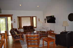 A living room with a sofa, chairs, a coffee table, a TV, and a lamp.