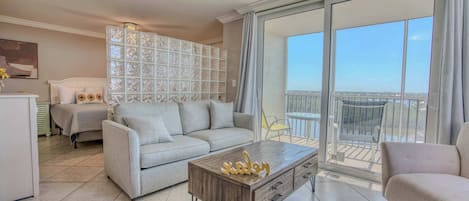 A modern living room with a sofa, a coffee table, and a balcony with a view.