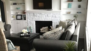 Una sala de estar con chimenea, televisor y estantería.