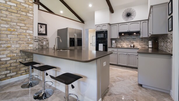 A modern kitchen with a central island, bar stools, and built-in appliances.