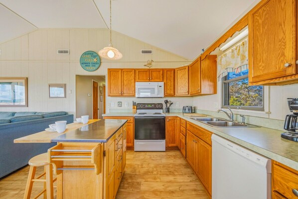 A compact kitchen with wooden cabinets, a microwave, stove, and a dishwasher.