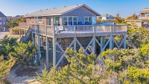 A beachfront house with a wooden deck and a glass-enclosed balcony. - Oceanfront Bella Beach Box - Dog Friendly w/ Hot Tub and Direct Beach Access (Avon)