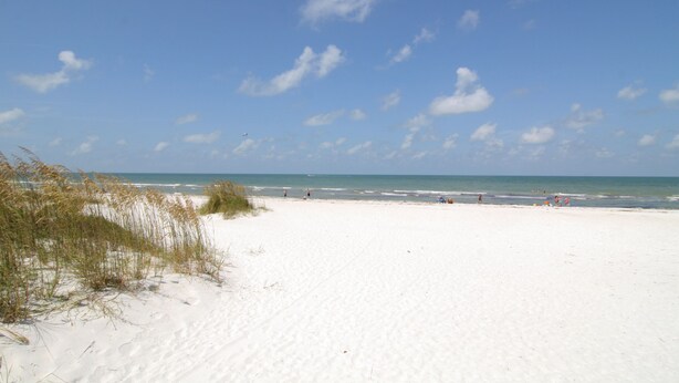 A beach with white sand and a clear blue sky.