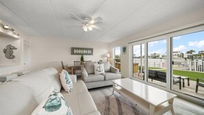 A spacious living room with a large window, a ceiling fan, and a view of the outdoors.