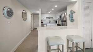 A modern kitchen with white cabinets, stainless steel appliances, and a central island with stools.