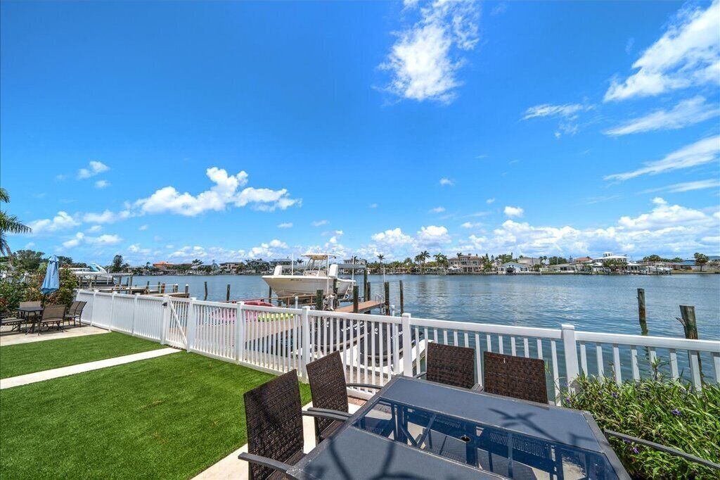 A waterfront patio with a view of the water, a dock, and a boat.