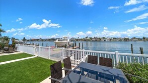 A waterfront patio with a view of the water, a dock, and a boat.