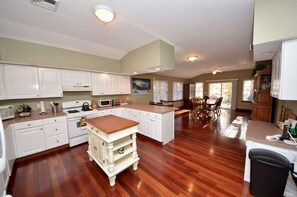 Una cocina amplia con armarios blancos, una isla central y un comedor con sillas de madera.