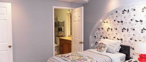 A bedroom with a bed, bedside table, and a wall with a bird pattern.