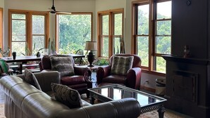 A spacious living room with leather sofas, a glass coffee table, and a fireplace.